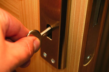 Someone unlocks a wooden door with a key in an escape room.