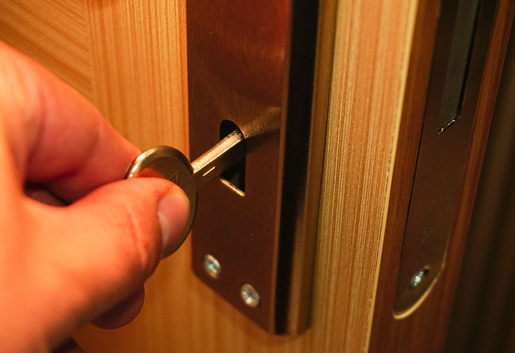 Someone unlocks a wooden door with a key in an escape room.